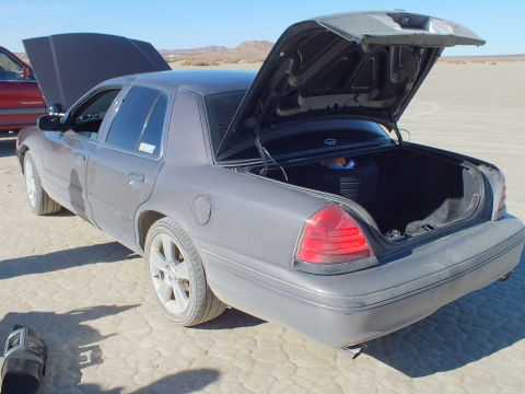 2003 Ford Crown Victoria - Rear three-quarter of a gray full-size Ford sedan, trunk and hood open on the lakebed