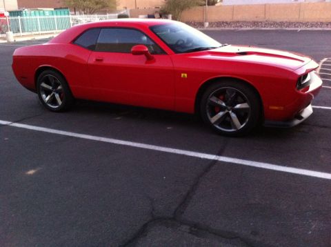 2010 Dodge Challenger - A red Dodge Challenger is parked in a lot, showing its side profile and front quarter view.