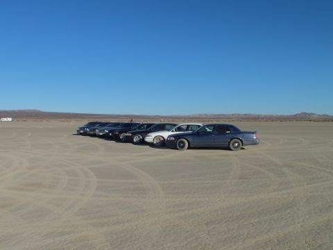 2003 Ford Crown Victoria - Several sedans grouped on desert hardpan ringed by tire tracks