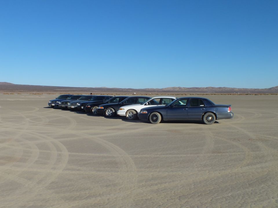 Row of sedans receding into distance on a dry desert lakebed