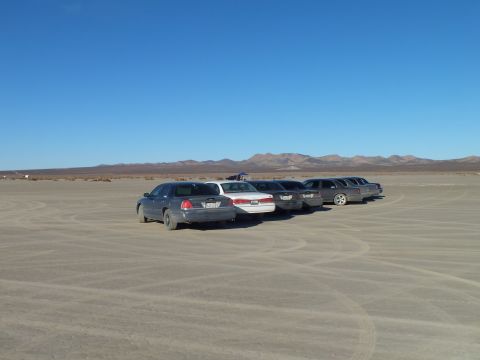 2003 Ford Crown Victoria - Sedans including a black car with roof beacon lined up on dry playa