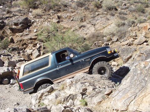 1993 Ford Bronco - This SUV is navigating a challenging rocky terrain.