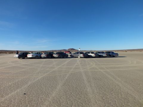 2003 Ford Crown Victoria - Wide view of a sedan and wagon meet on desert hardpan under blue sky