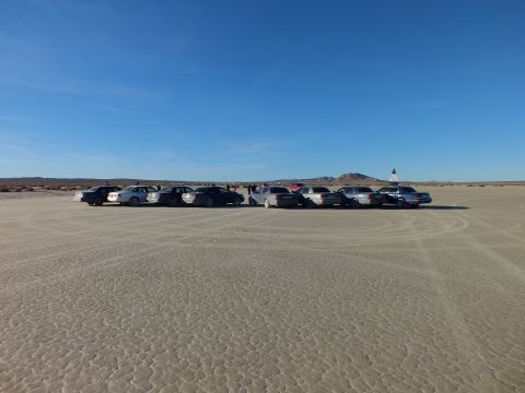 2003 Ford Crown Victoria - Wide lineup of vehicles on playa with people gathered near the center