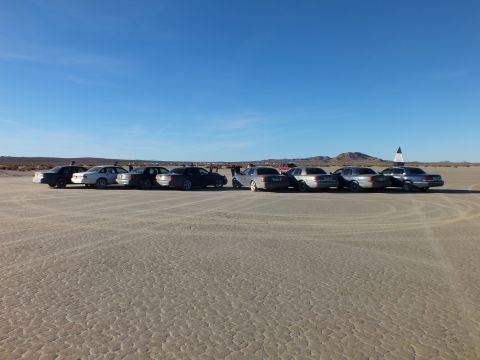 2003 Ford Crown Victoria - Sedans and wagons staged on hardpan with a crowd and red SUV behind