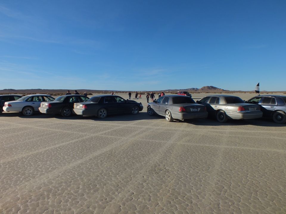 Two rows of sedans parked facing each other on a desert lakebed