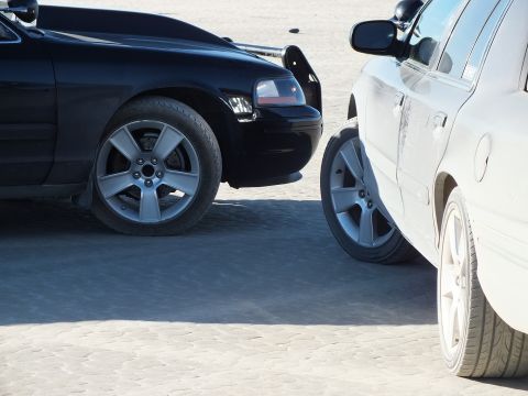 2003 Ford Crown Victoria - Front clip of a dark Crown Victoria nose-to-nose with a dusty white sedan on packed desert ground.