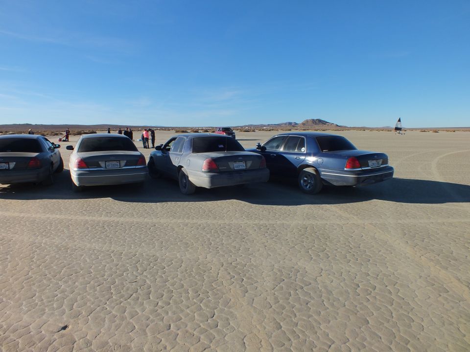 Rear view of four Ford Crown Victoria and Mercury sedans parked on desert lakebed