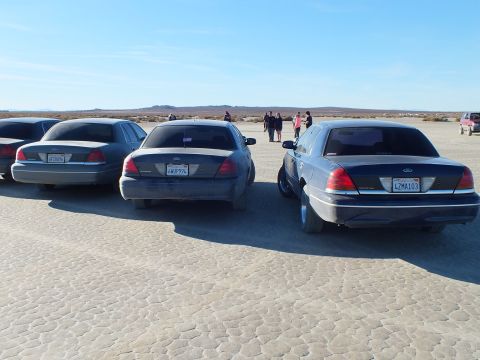 2003 Ford Crown Victoria - Rear quarter of three Panther Fords on desert flat; visible plates 4AMP99L and 4ZMA103.