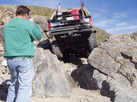 1993 Ford Bronco - A man photographs a 1993 Ford Bronco navigating a rocky off-road trail.