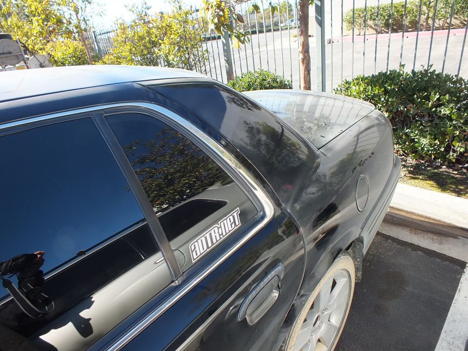 Black sedan rear quarter and C-pillar with SUPERMOTORS.NET watermark decal