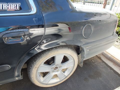 2003 Ford Crown Victoria - Close shot of a black sedan's rear fender, fuel filler door and five-spoke alloy wheel.