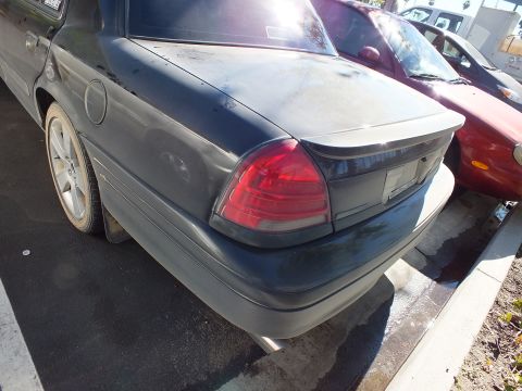 2003 Ford Crown Victoria - Rear corner of a dark Ford Crown Victoria with chrome dual exhaust tip and red tail light.