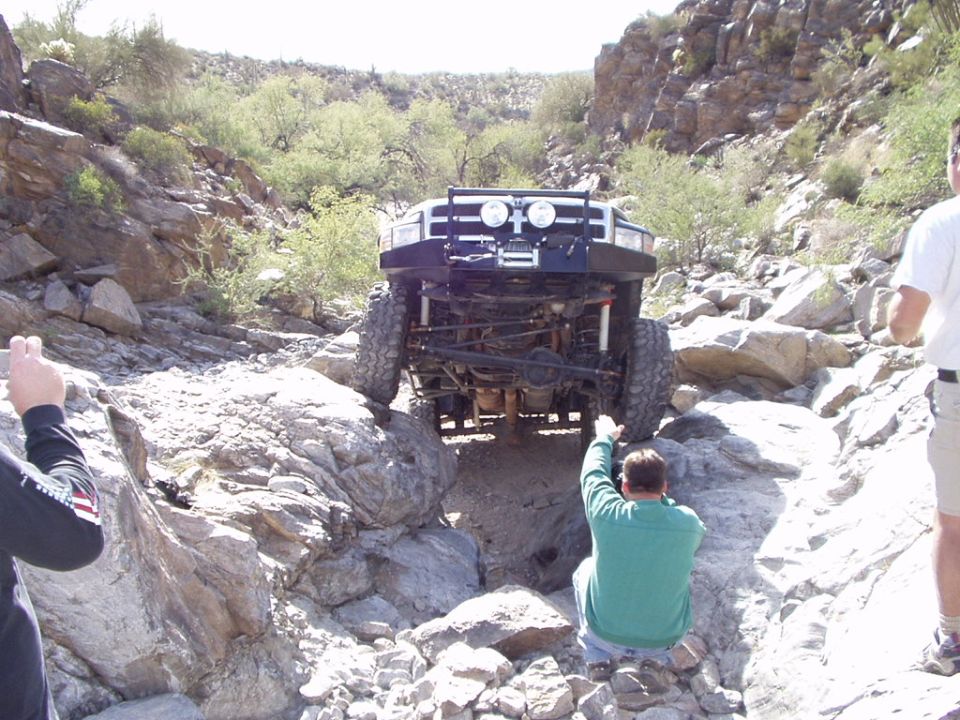 Dark blue lifted 4x4 crawling rocks with front axle and undercarriage visible