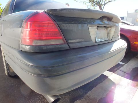 2003 Ford Crown Victoria - Dark Ford Crown Victoria trunk showing a Police Interceptor badge and chrome exhaust tip.