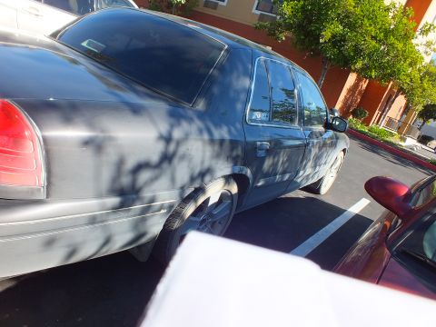 2003 Ford Crown Victoria - Driver-side profile of a dark Crown Victoria sedan with shadows across the doors.