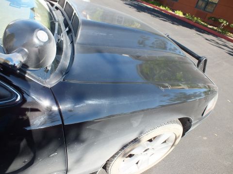 2003 Ford Crown Victoria - Close view across a black car's hood and cowl with a side mirror and alloy wheel.