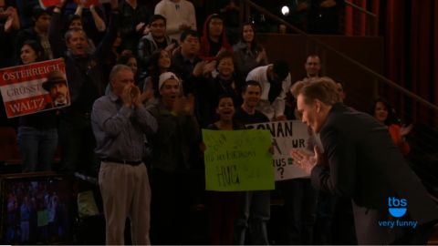 1993 Ford Taurus - An audience watches a performance, with some holding signs and clapping.