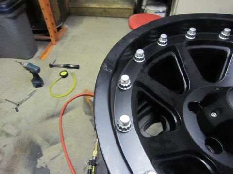 2008 Jeep Wrangler - A black wheel with lug nuts is shown, with tools and a tire pressure gauge on the floor.