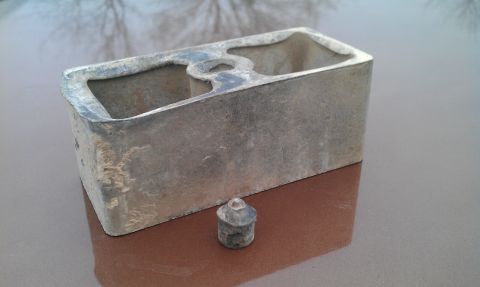 1987 Ford Bronco - A metal component and a small cap are shown against a reflective background.