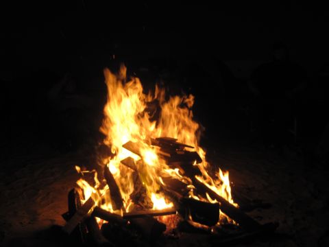 1989 Ford Bronco - A campfire burns brightly in the dark, illuminating logs and flames.