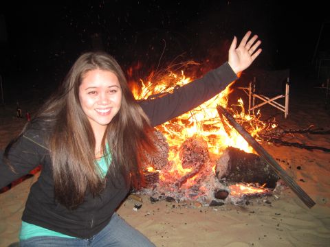 1989 Ford Bronco - A woman poses for a photo in front of a roaring campfire on a sandy beach.