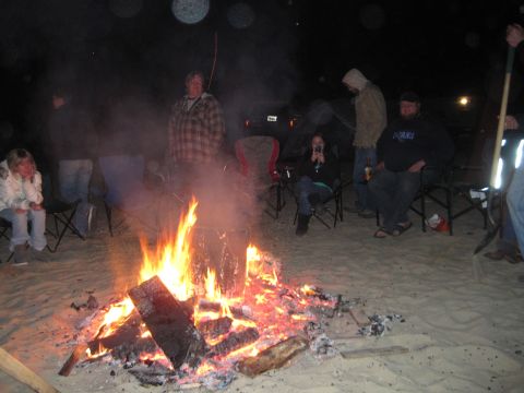1989 Ford Bronco - People gather around a bright campfire on a sandy beach at night.