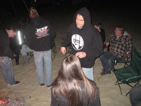 1989 Ford Bronco - A group of friends enjoy a campfire on the beach at night, with several people wearing hoodies.