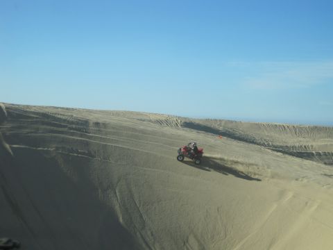 1989 Ford Bronco - An ATV navigates a sandy slope, leaving a trail of dust against the horizon.