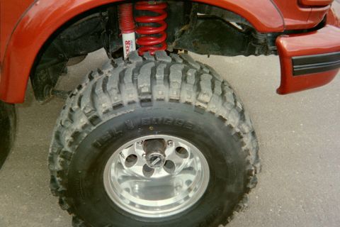 1995 Ford Bronco - Detail of a lifted vehicle's suspension and aggressive tread tire.