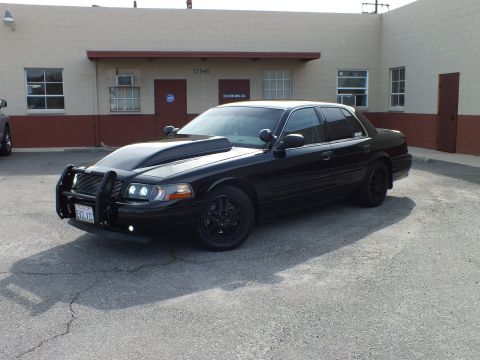 2003 Ford Crown Victoria - Murdered-out Crown Victoria Police Interceptor, front three-quarter view with grille guard outside Custom Mfg Co.