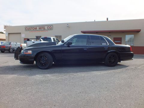 2003 Ford Crown Victoria - Full side view of a murdered-out Crown Victoria sedan parked outside Custom Mfg Co.
