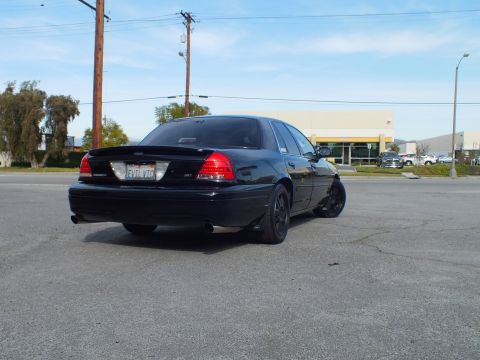 2003 Ford Crown Victoria - Full rear shot of a blacked-out sedan on pavement, California license plate centered under decklid