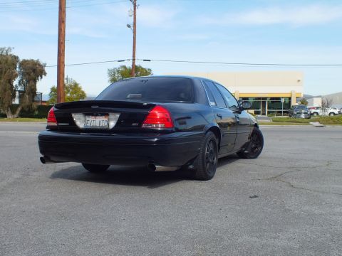 2003 Ford Crown Victoria - Rear three-quarter of a blacked-out sedan parked in a lot, red taillights and California plate visible