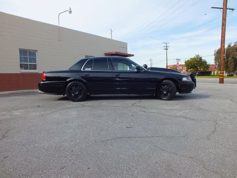 2003 Ford Crown Victoria - Driver-side profile of a blacked-out sedan with low stance and black aftermarket wheels