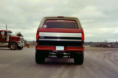 1995 Ford Bronco - Lifted Ford Bronco parked next to a semi-truck under an overcast sky.