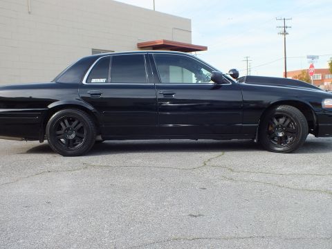 2003 Ford Crown Victoria - Driver-side profile of a blacked-out sedan, chrome window surrounds and dark wheels in view