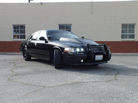 2003 Ford Crown Victoria - Front quarter of a blacked-out sedan showing a chrome push bar with Ford oval emblem
