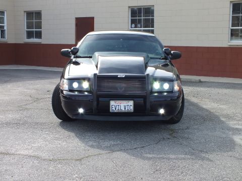 2003 Ford Crown Victoria - Head-on front shot of a blacked-out sedan with hood scoop and California plate reading EVIL VIC