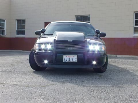 2003 Ford Crown Victoria - Front-on shot of a blacked-out Crown Victoria, all six lights blazing, EVIL VIC plate centered on a billet grille.