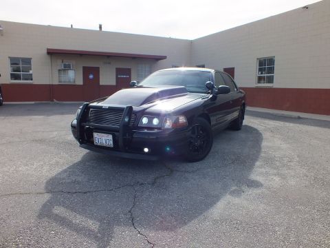 2003 Ford Crown Victoria - Front-quarter view of the blacked-out Interceptor with a tubular grille guard and EVIL VIC California plate.