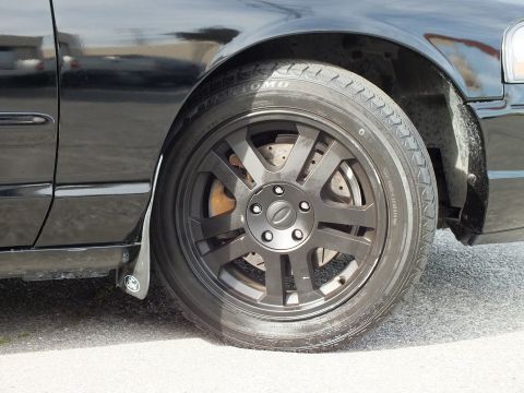 2003 Ford Crown Victoria - Tight wheel shot of the Crown Vic showing the black rim, Ford center cap and a Toyo tire sidewall.