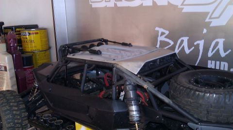 1996 Ford Bronco - RC rock crawler with a prominent roll cage and spare tire, set against a wall with 'Baja' graphics.