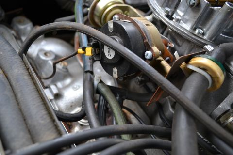 1978 Ford Bronco - Detail of engine components, including a carburetor and various hoses, with a visible part number on a black electrical component.