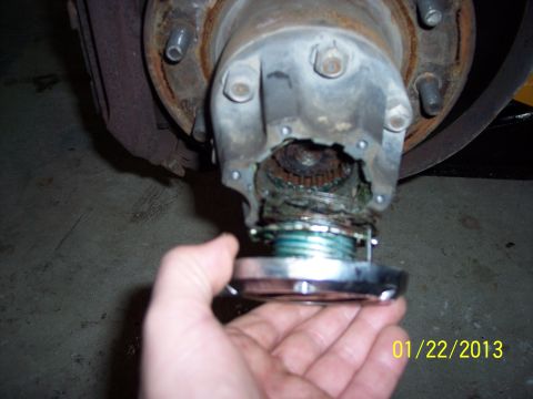 1973 Ford F-250 - Close-up of a damaged front wheel hub assembly, showing exposed gears and grease, with a locking hub being held.