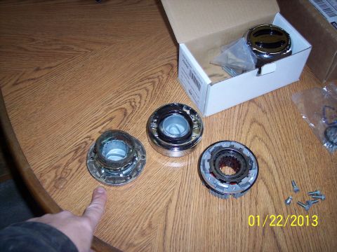 1973 Ford F-250 - Three free-wheeling hubs are displayed on a wooden surface, with one still in its original packaging.