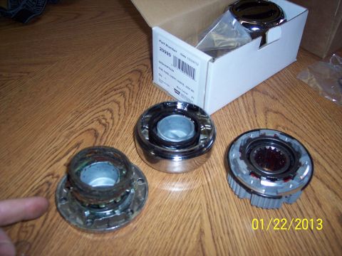 1973 Ford F-250 - Aftermarket hub assembly parts are laid out on a wooden surface next to their packaging.