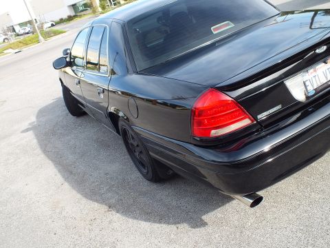 2003 Ford Crown Victoria - Close rear-quarter of the black Crown Victoria, lit taillight, blacked-out wheel and chrome exhaust tip.