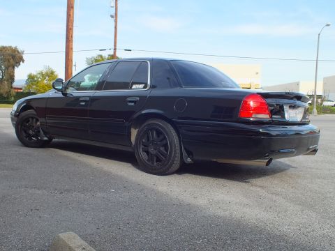 2003 Ford Crown Victoria - Blacked-out Crown Victoria shot from behind with red tail lights lit and tinted glass.