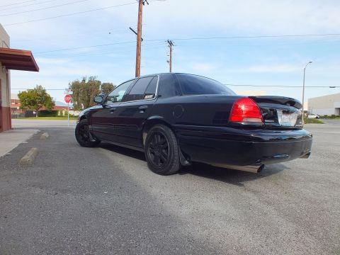 2003 Ford Crown Victoria - Low rear angle of a murdered-out Crown Victoria parked on a lot near a stop sign.